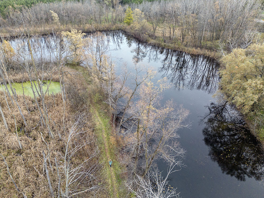 Aerial view showing the artist walking along a lakeside trail.