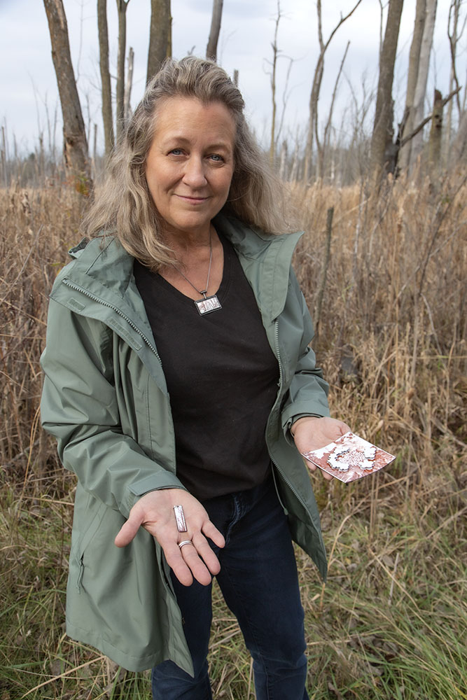 The artist with a pendant inspired by CESA trees and a wall plaque inspired by CESA flowers.