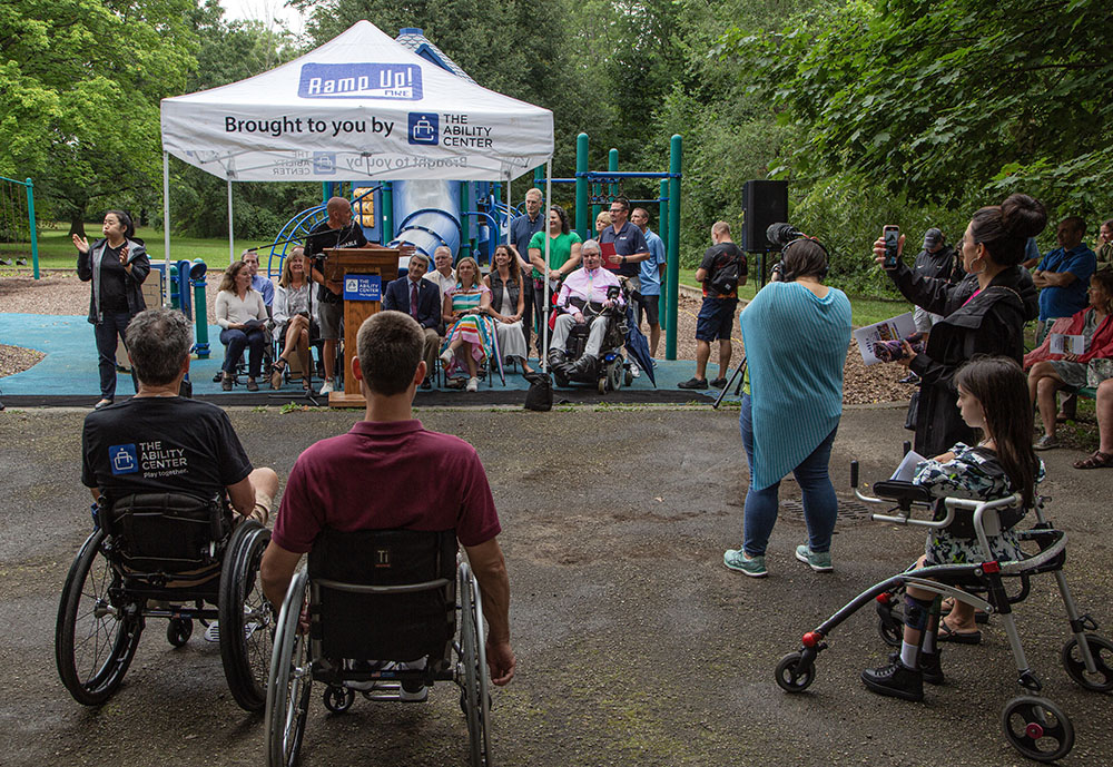 Well over a hundred people stood--and sat in their wheelchairs--in the rain to listen as dignitary after dignitary spoke at the groundbreaking of what is projected to be the "most accessible park in the nation." Wisconsin Avenue Park in Wauwatosa was officially renamed Moss Park at the event, in honor of the primary donor who made it possible.