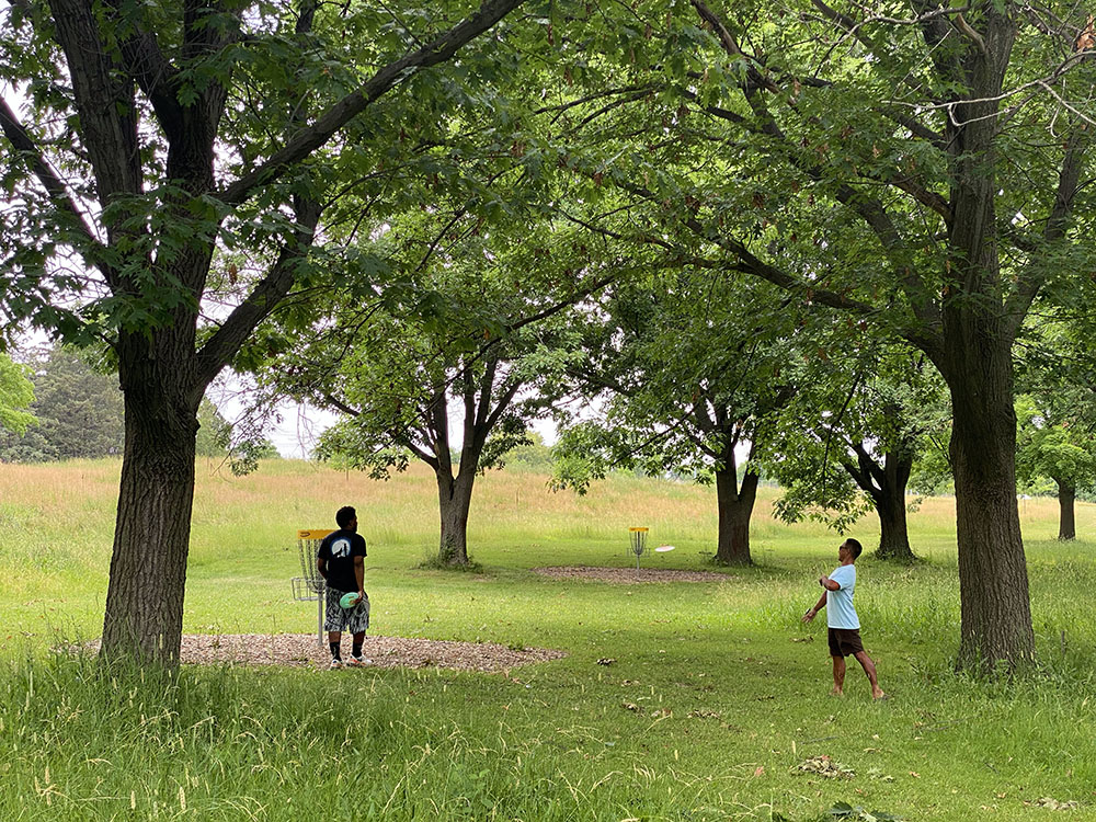 A couple take a break from walking to use the Dineen Disc Golf Course.