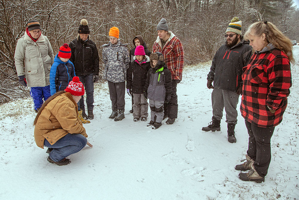 DNR educator Katie Whitstone and group studying rabbit tracks.