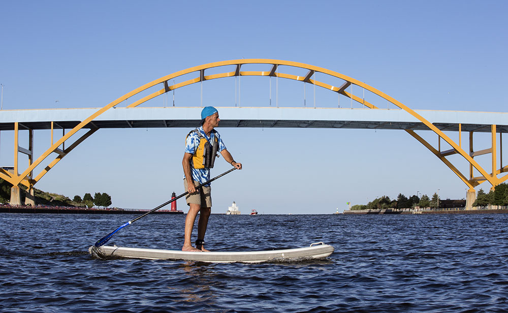 Framed by the Hoan Bridge, a paddleboarder navigates the mouth of the harbor, which is also the confluence of the Milwaukee and Kinnickinnic Rivers.