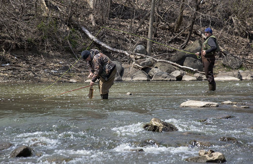 Two anglers fishing just below the Horlick Dam. One is releasing a sucker he caught. 