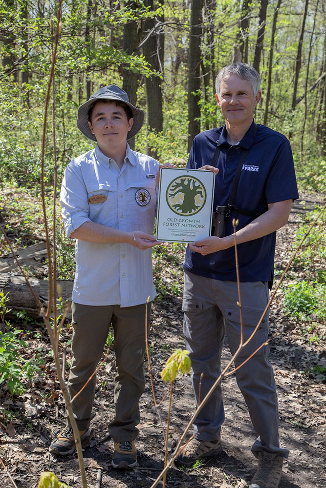 Nick Sanchez, OGFN Network Manager, presenting the Old-Growth Forest Network sign to Brian Russart, Mke Co Parks Natural Areas Supervisor.