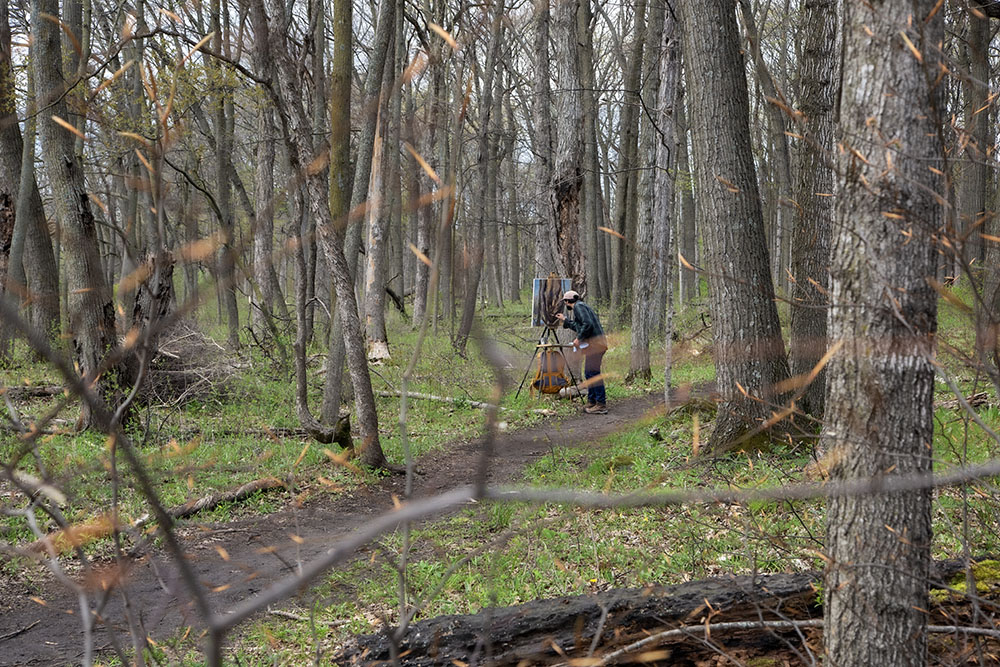 Hector Acuna working on his painting in the woods.