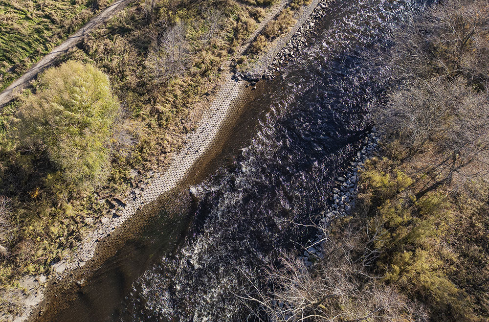 Aerial view taken in 2023 showing close up a portion of the "flume" between North Ave and the former dam where sediments have been impounded, the riverbank buttressed to contain them.