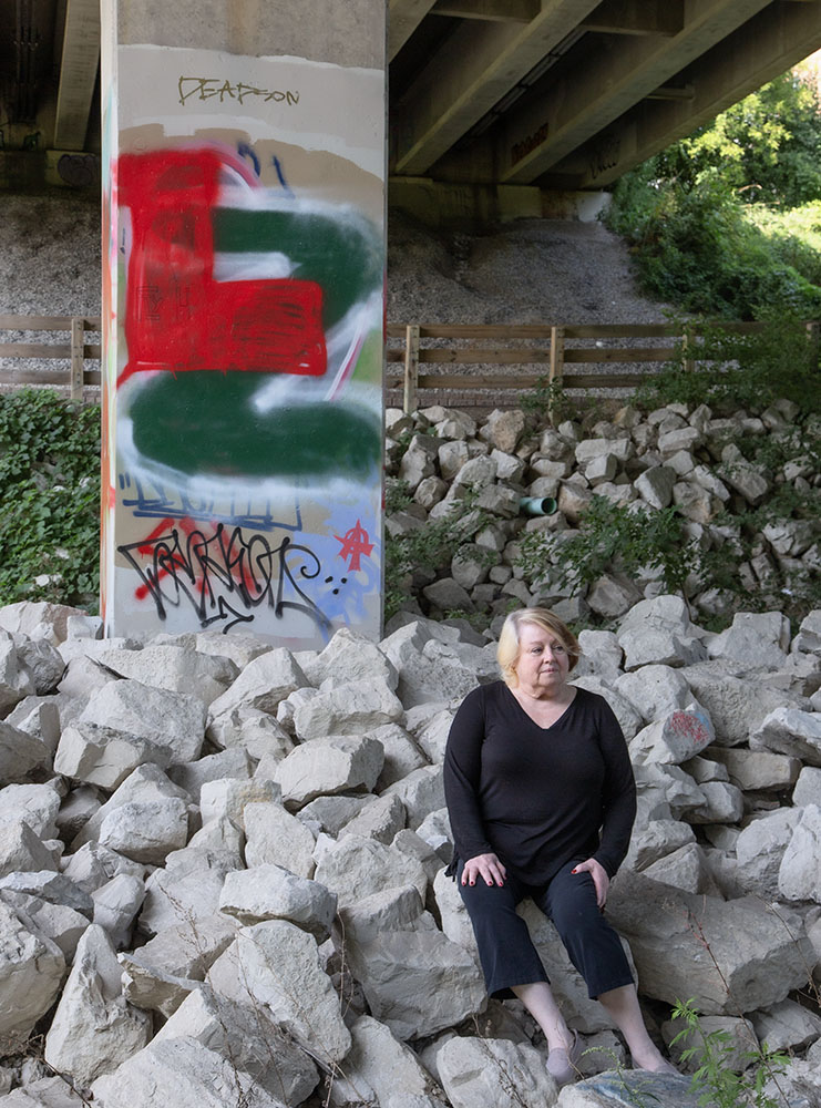 The artist sitting at the edge of the river under the North Avenue Bridge. 