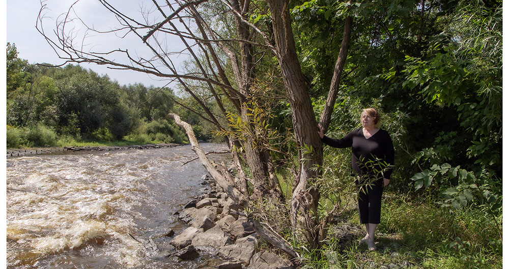 Artist in residence Clare Jorgensen standing next to the Milwaukee River