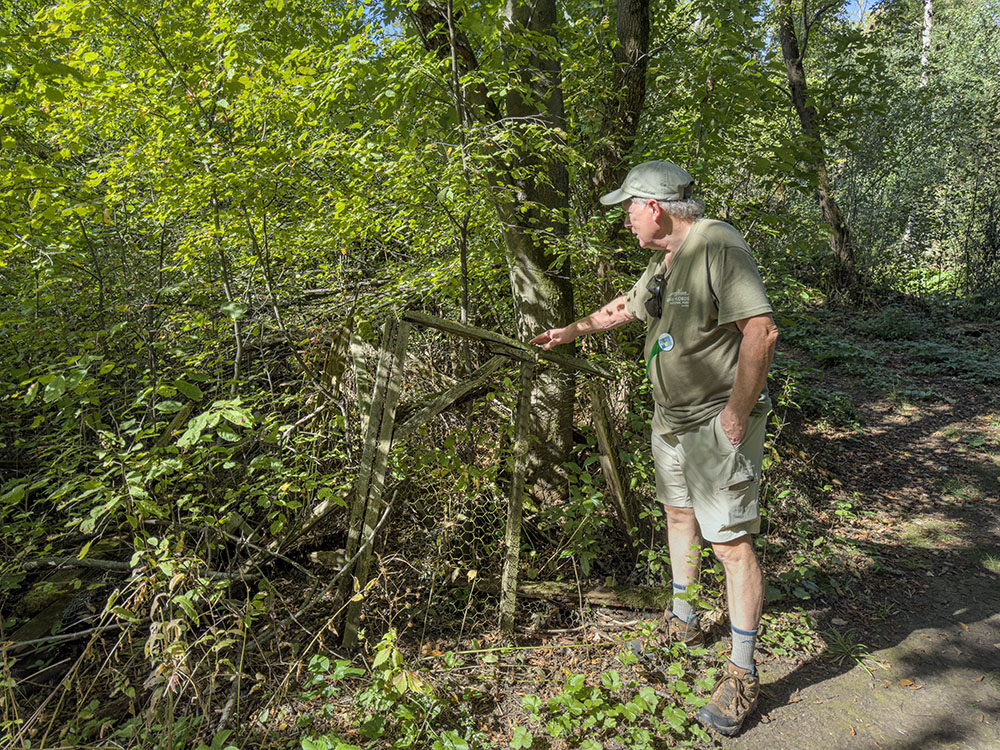 Richard, a volunteer tour guide, points out one of the fox farm ruins visible next to the trail.