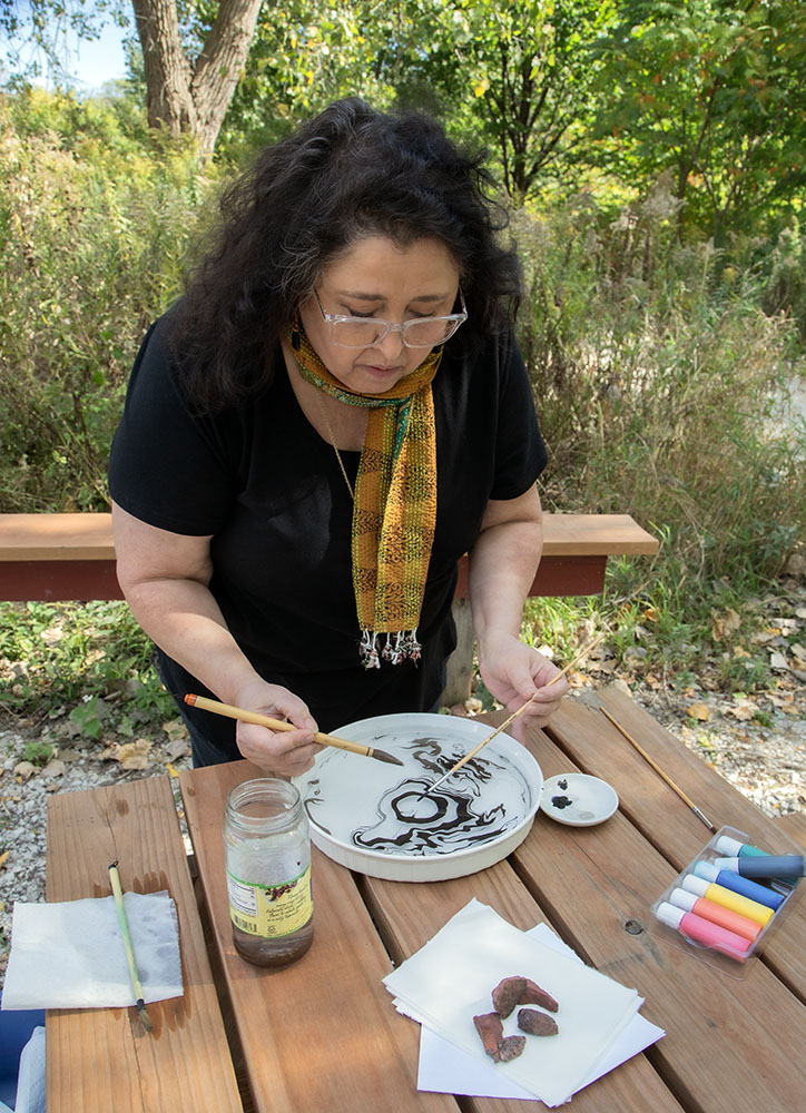 Dara Larson demonstrates the marbling technique on a picnic table in Turtle Park.