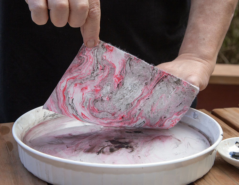 Lifting the paper from the tray of water/ink.