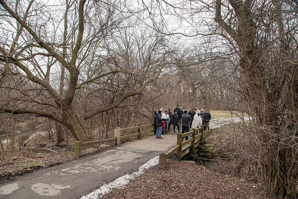 The group pauses at the outflow from the park lagoon to the Kinnickinnic River to learn about plans to revitalize the river and the park.