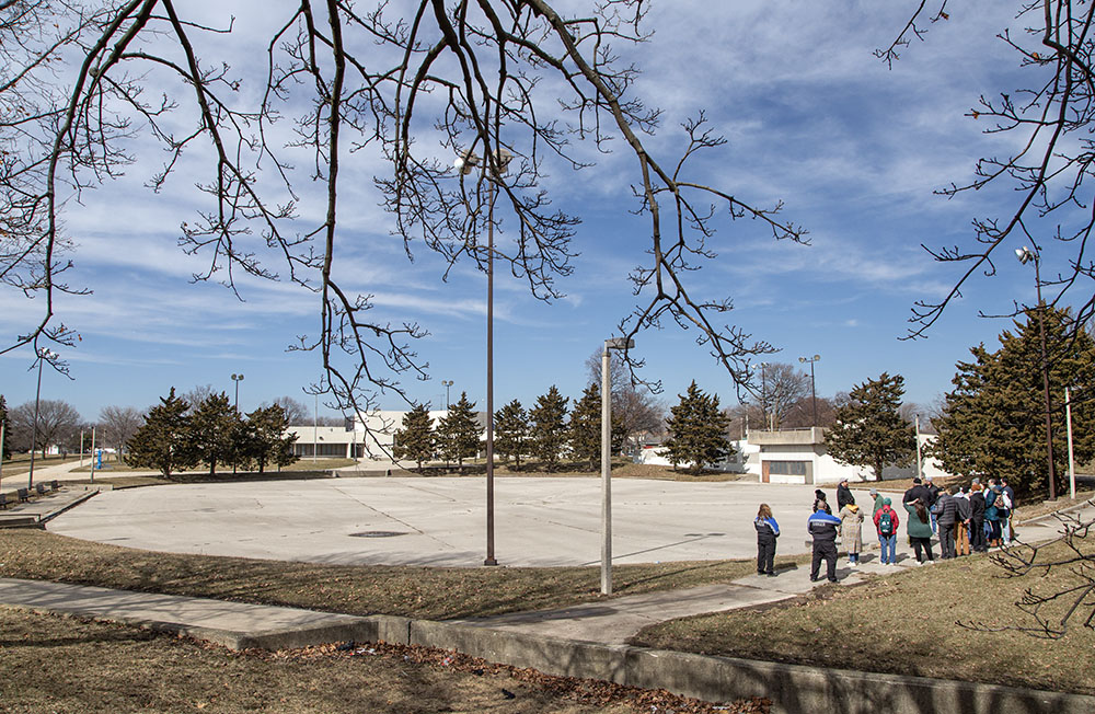 The group pauses to learn about the former roller rink. The Dr. Martin Luther King Jr. Community Center is in the background.