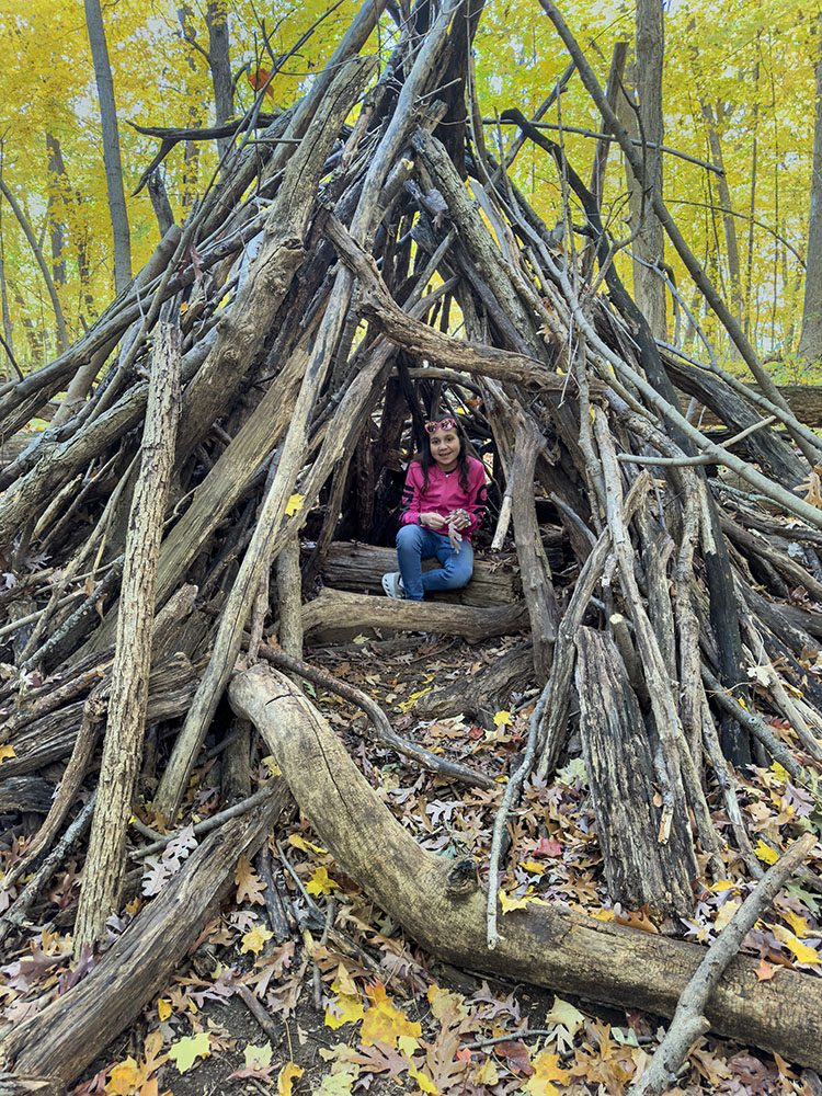 Lynn inside a large stick fort.