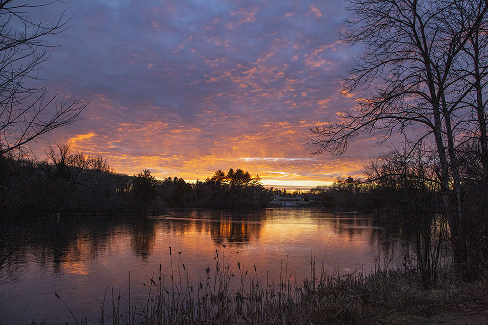 A flaming sunset reflected in the frozen lagoon at Greenfield Park, West Allis.