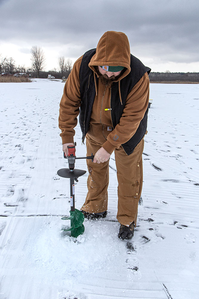 Using an ice auger to make a hole for fishing at Ottawa Lake State Recreation Area.