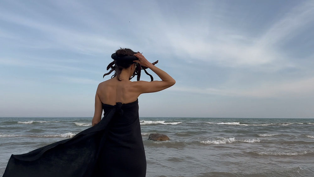 The artist at Lake Michigan with a mask she made from scavenged black locust seed pods.