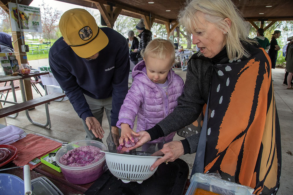 Volunteer Tori Tasch helps a youngster create a seed packet with biodegradable paper pulp.