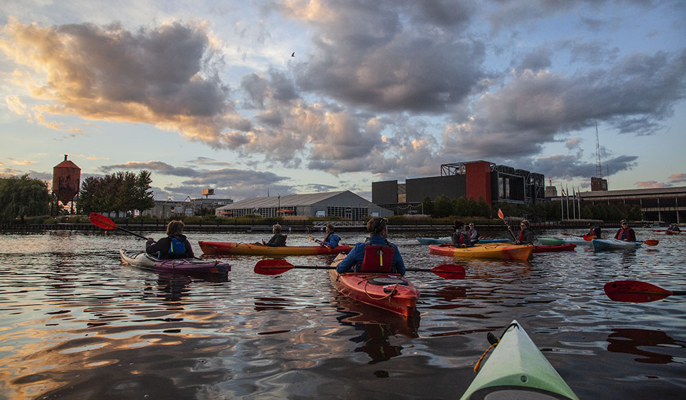 A sunset kayak tour pauses next to the Harley Davidson museum, one of the attractions along the Menomonee River in the Menomonee Valley.
