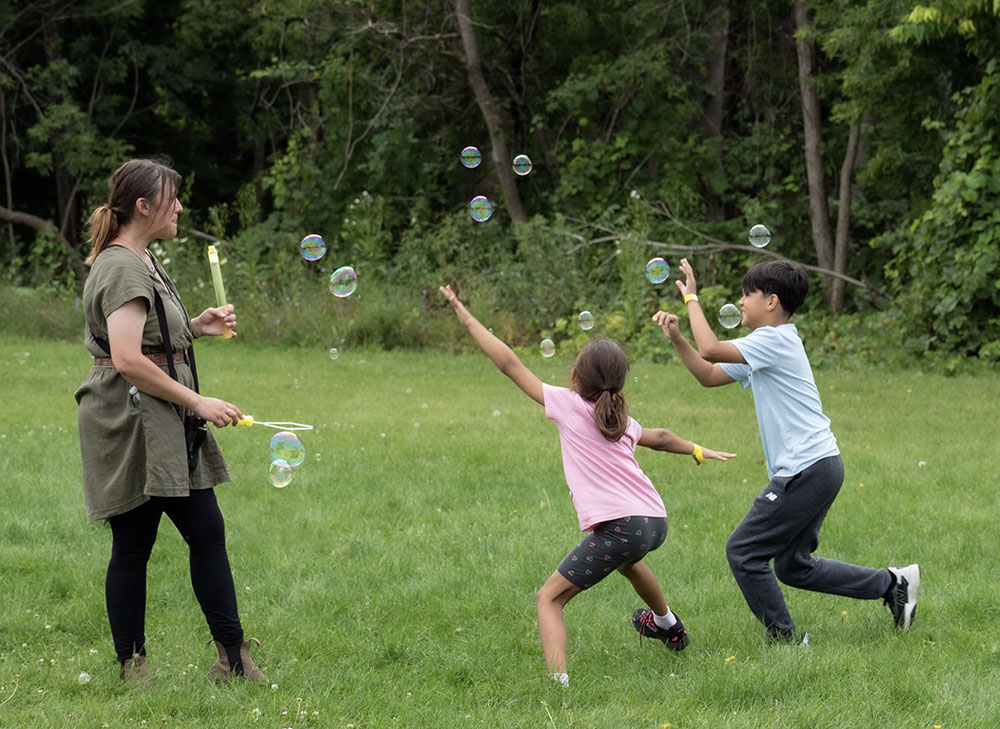 Milwaukee County Parks Community Engagement Coordinator Danielle Pahlisch blows bubbles for a couple happy kids.