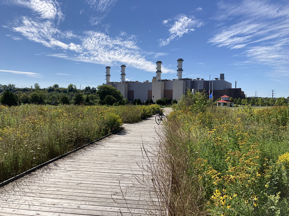 A boardwalk passes through prairie in the shadow of Port’s power plant.