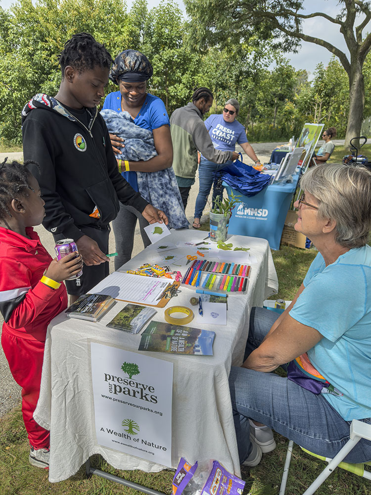 Board member Laurie Muench and visitors to the POP table.