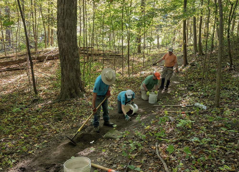 The dirt accumulated by grading the trail is collected in 5-gallon buckets and strewn in the woods nearby.