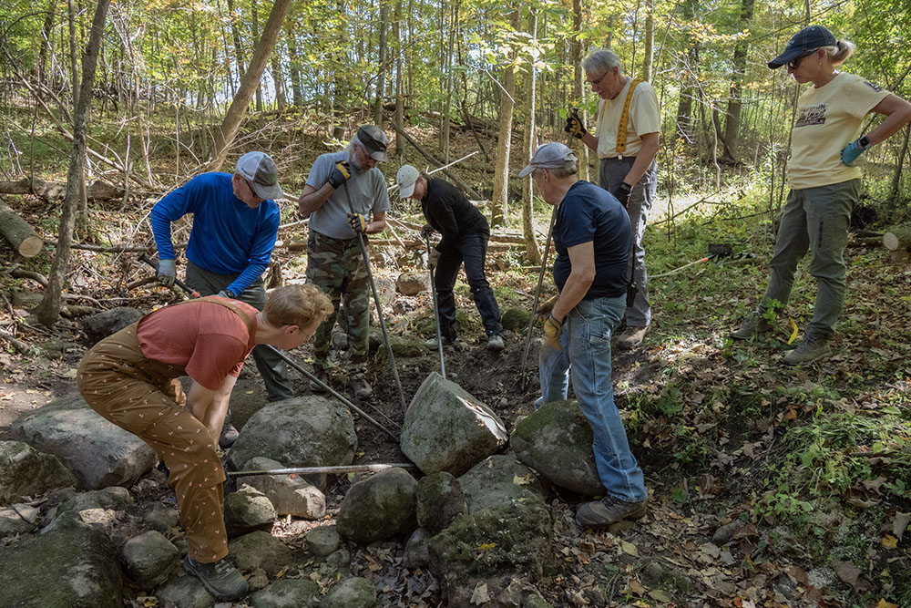 The team using steel bars to adjust the position of one of the stepping stones.