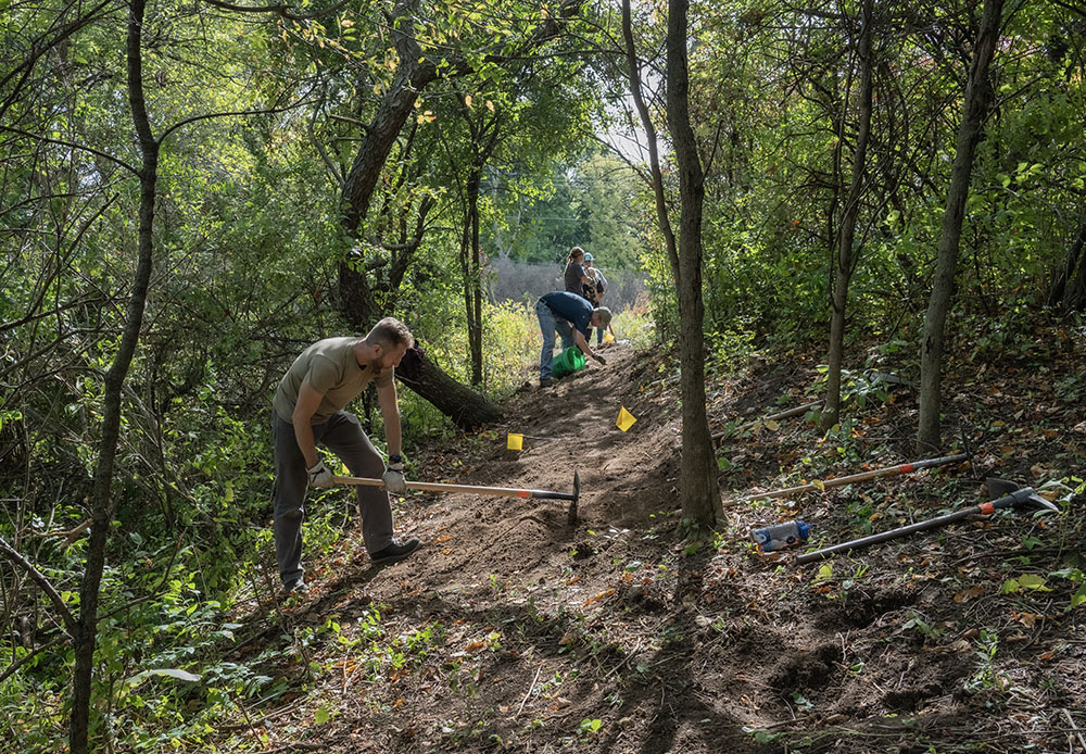 A volunteer uses a McLeod tool to cut the trail into the slope of a ridge.