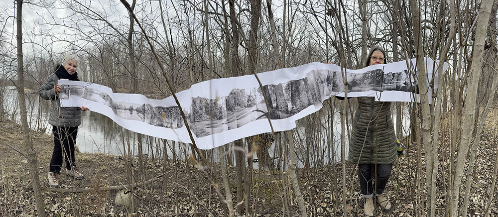 The artists with a mock-up of an accordion book next to the Milwaukee River at Fellenz Woods.