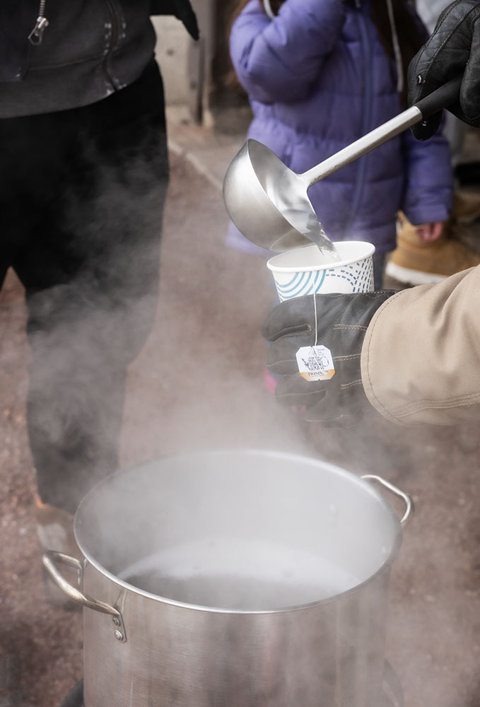 Participants are invited to indulge in a cup of tea steeped in the boiling sap.