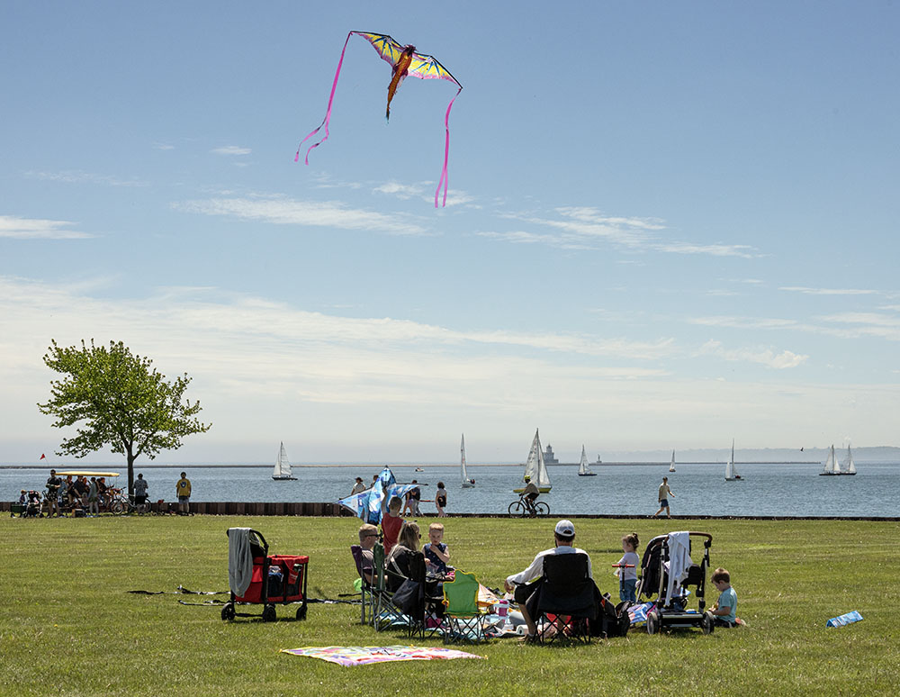 Sailboats in the harbor form a backdrop for high-flying kites.