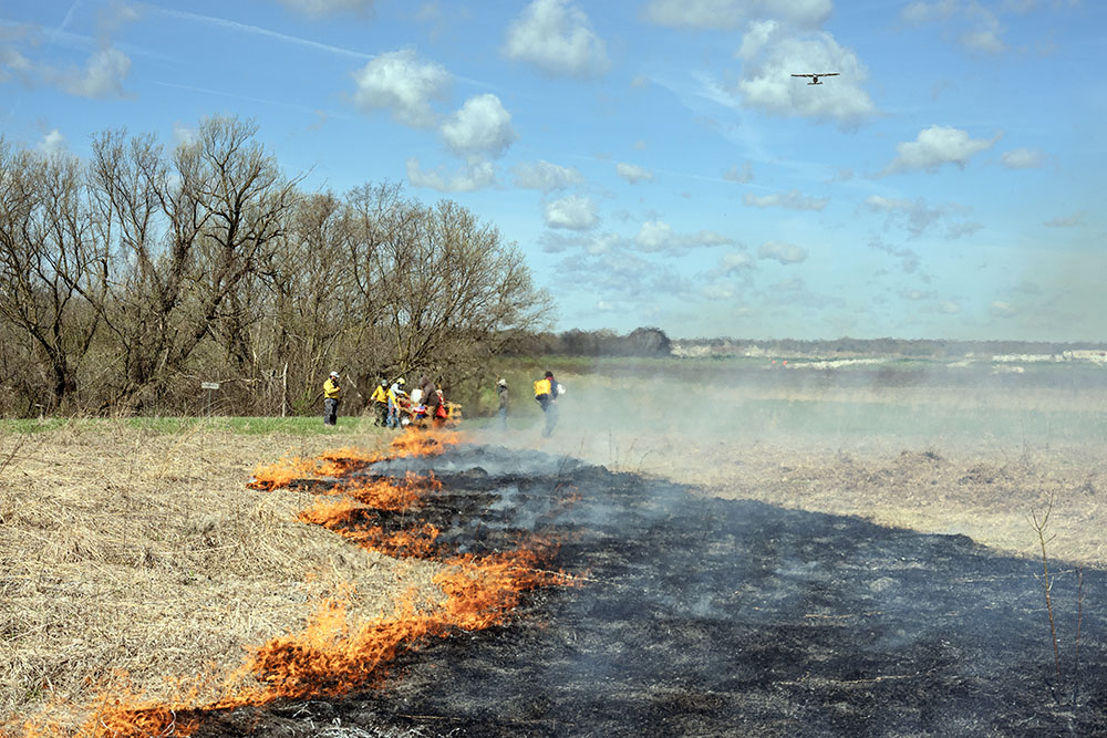A small plane takes off over the smoke from the burn.