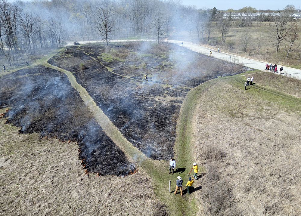Aerial view of the first section of prairie to burn with spectators gathered on the road.