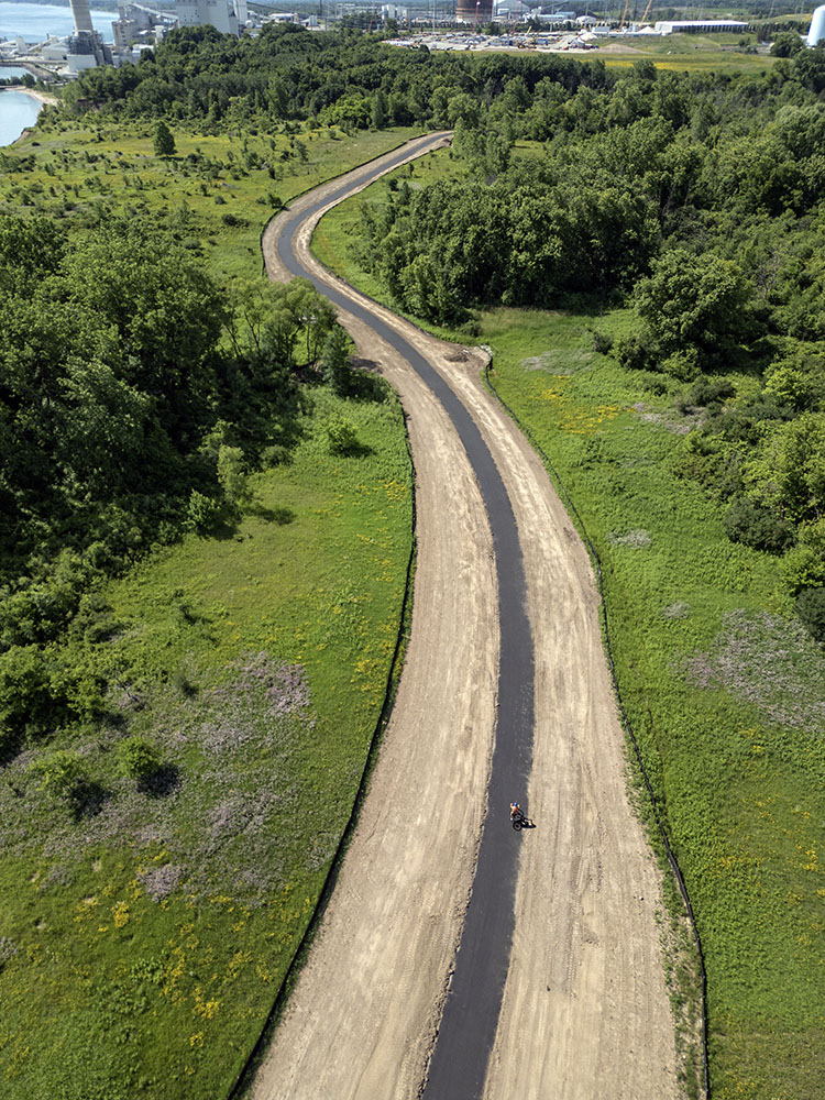 By early July some portions of the new trail were paved. If you look close you can spot a lone cyclist trying it out.
