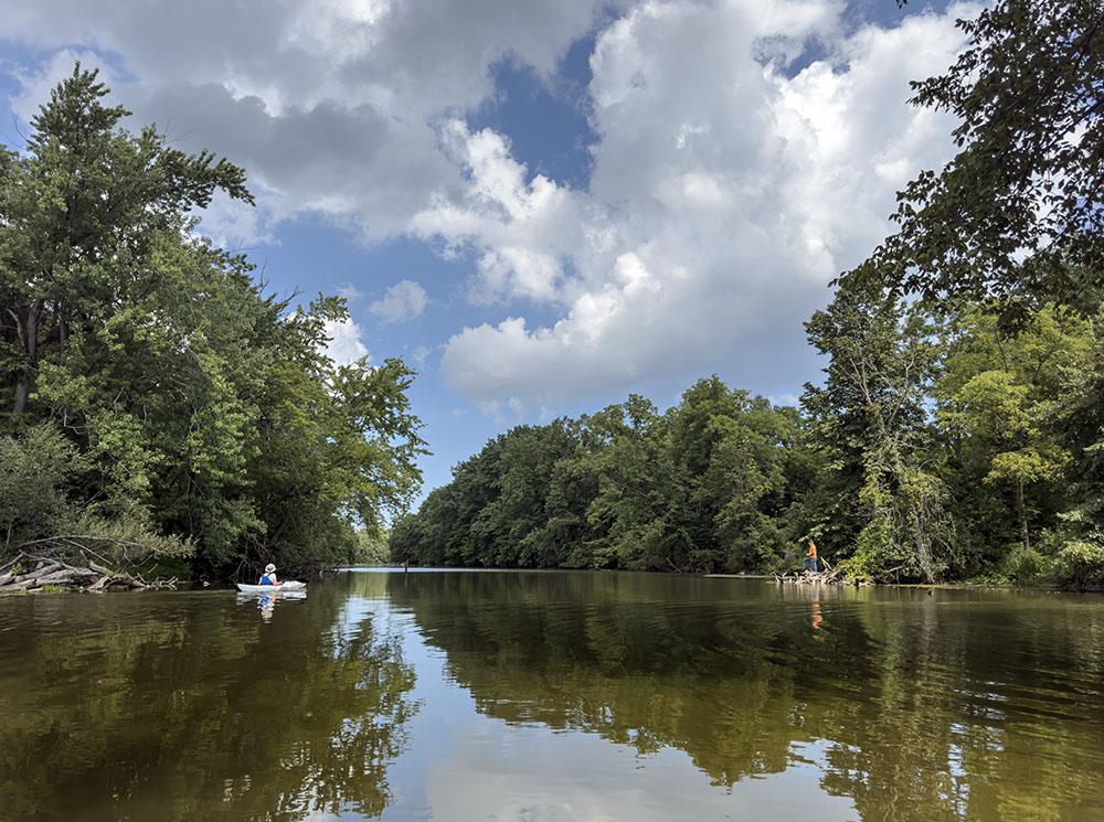 A kayaker and an angler face off across the Root River here at River Bend Nature Center in Racine. The river is still pooled here by the Horlick Dam downstream, but won't be much longer. As reported in 2024, the dam is slated for removal.