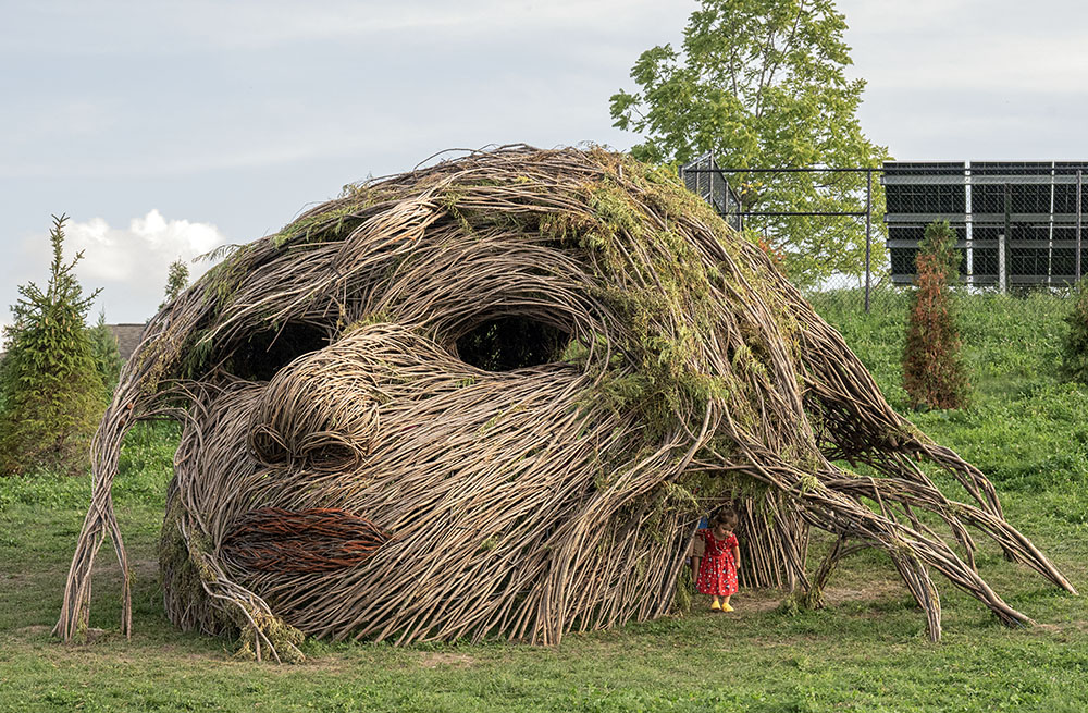 A youngster discovers the kid-size entrance underneath Sacred Rhythm Mother's flowing hair.