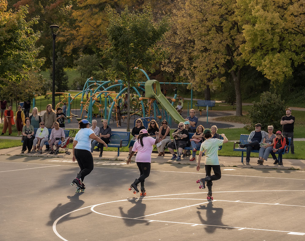 A trio of Milwaukee Rhythm Skaters uses a basketball court as a dance venue.