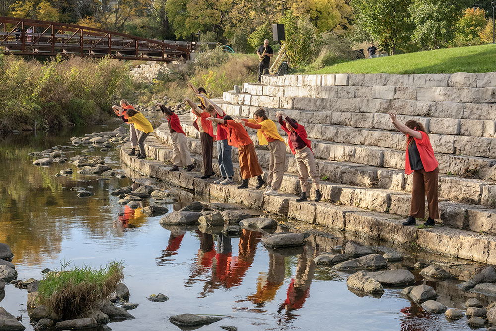 dancers posing along the KK River reflected in the water