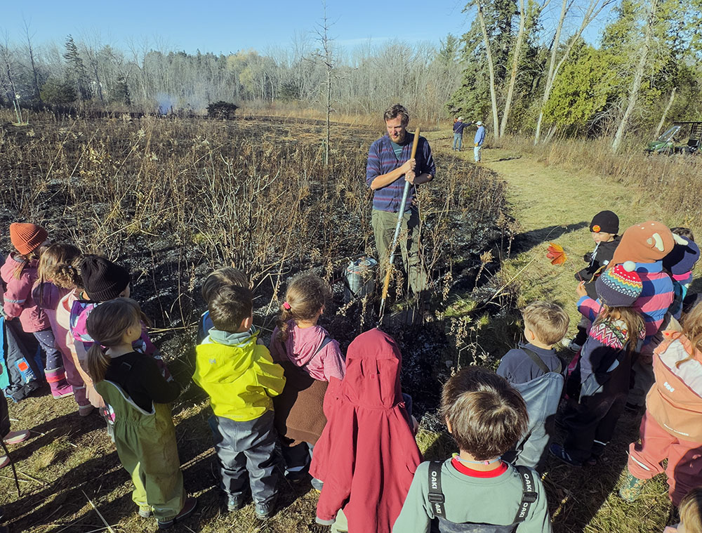 The children listen as Schlitz Audubon staffer explains how the burning is done.