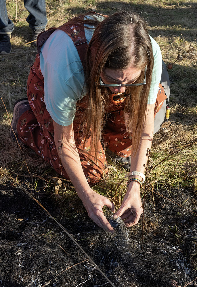 One of the teachers collects ash and charcoal to take back to the classroom.
