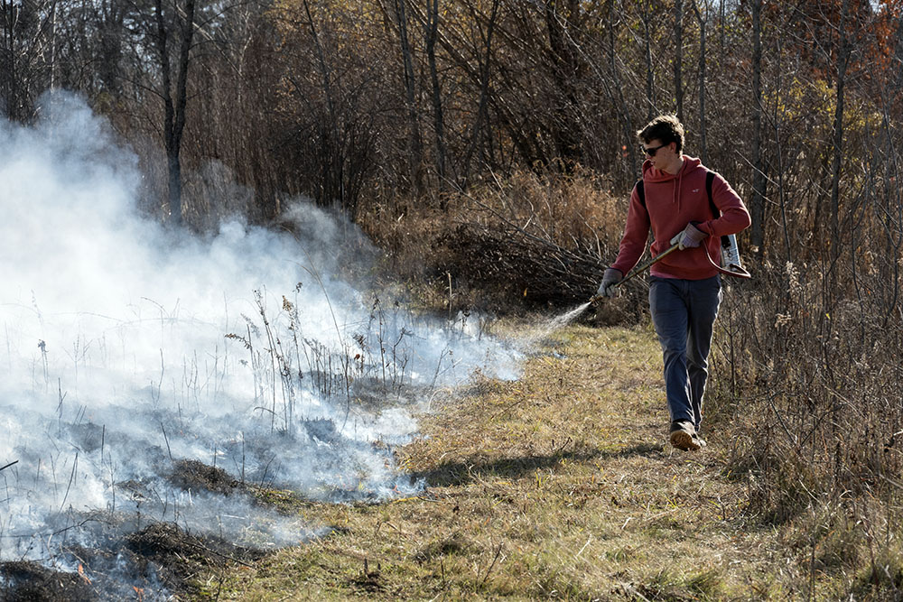 A volunteer uses a sprayer along the break line to help contain the fire.